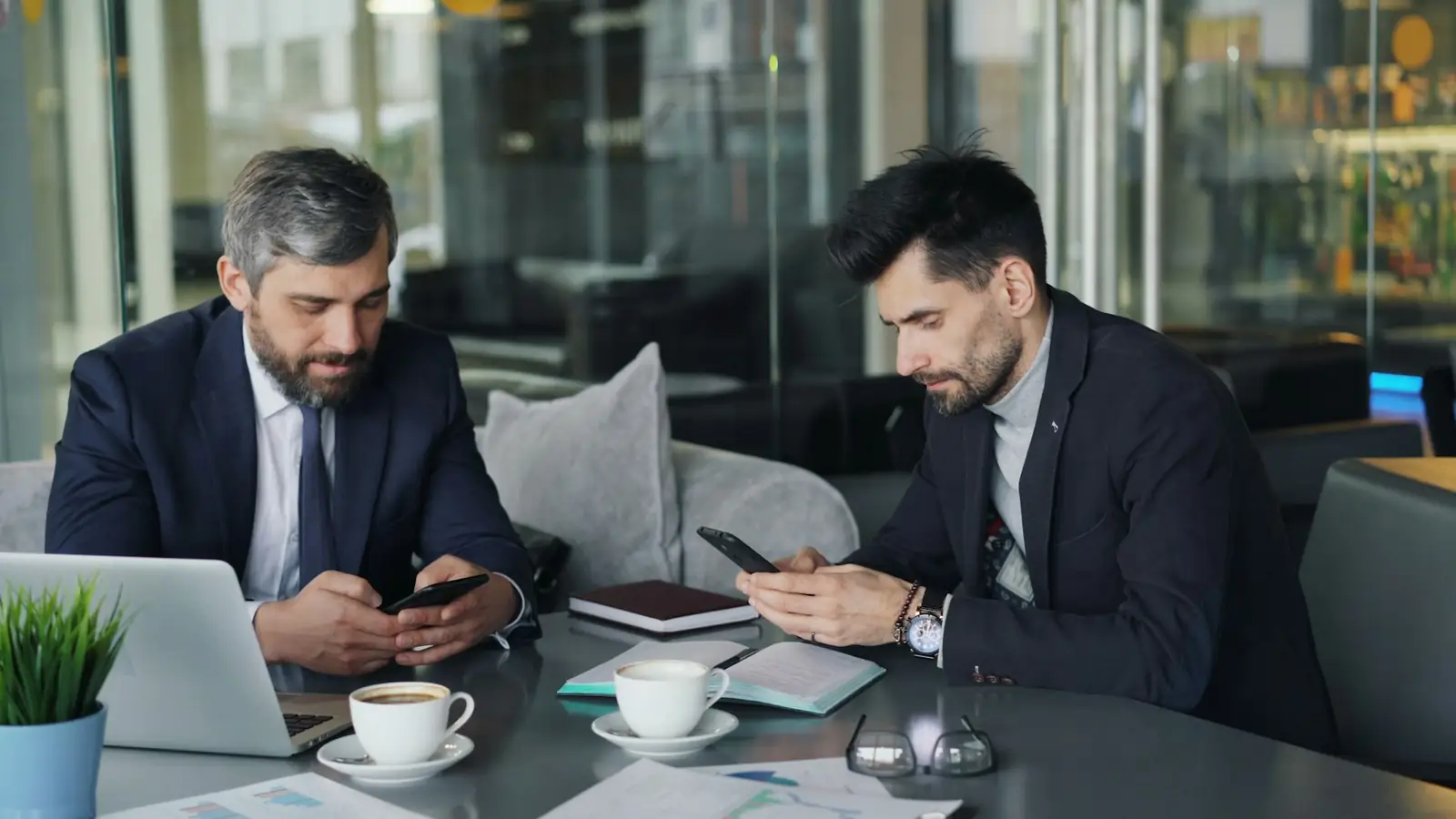 Two businessmen reviewing information on their smartphones during a partnership discussion