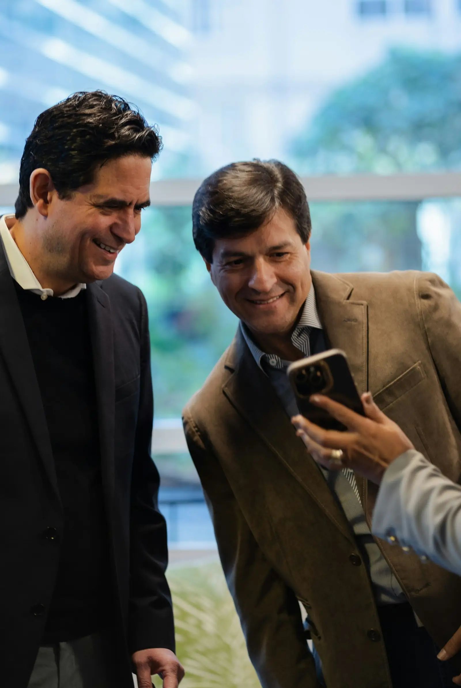 Two business partners smiling while reviewing a smartphone together