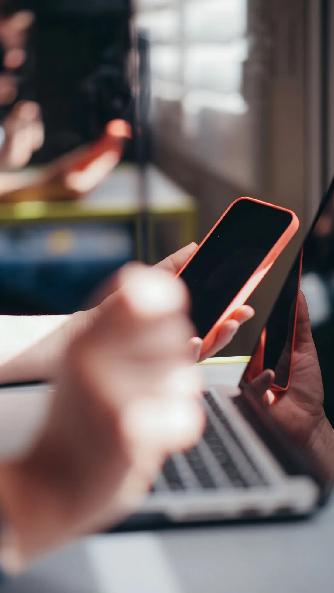 Person using a smartphone alongside a laptop to manage a digital financing application